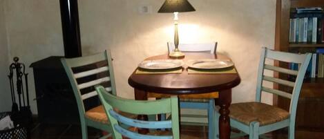 Un coin repas comprenant une table et des chaises, une lampe, un tableau au mur et une bibliothèque.