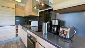 Una cuina moderna amb armaris de fusta, microones, cafetera i torradora.