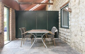Un patio con un tavolo e quattro sedie, un muro in mattoni e una finestra.