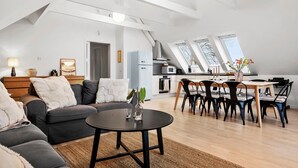 A modern living room with a sofa, a coffee table, and a dining area with chairs and a table.