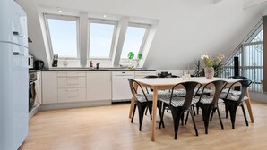 A modern kitchen with white cabinets, a dining area with striped chairs, and large windows offering a view of the outdoors.
