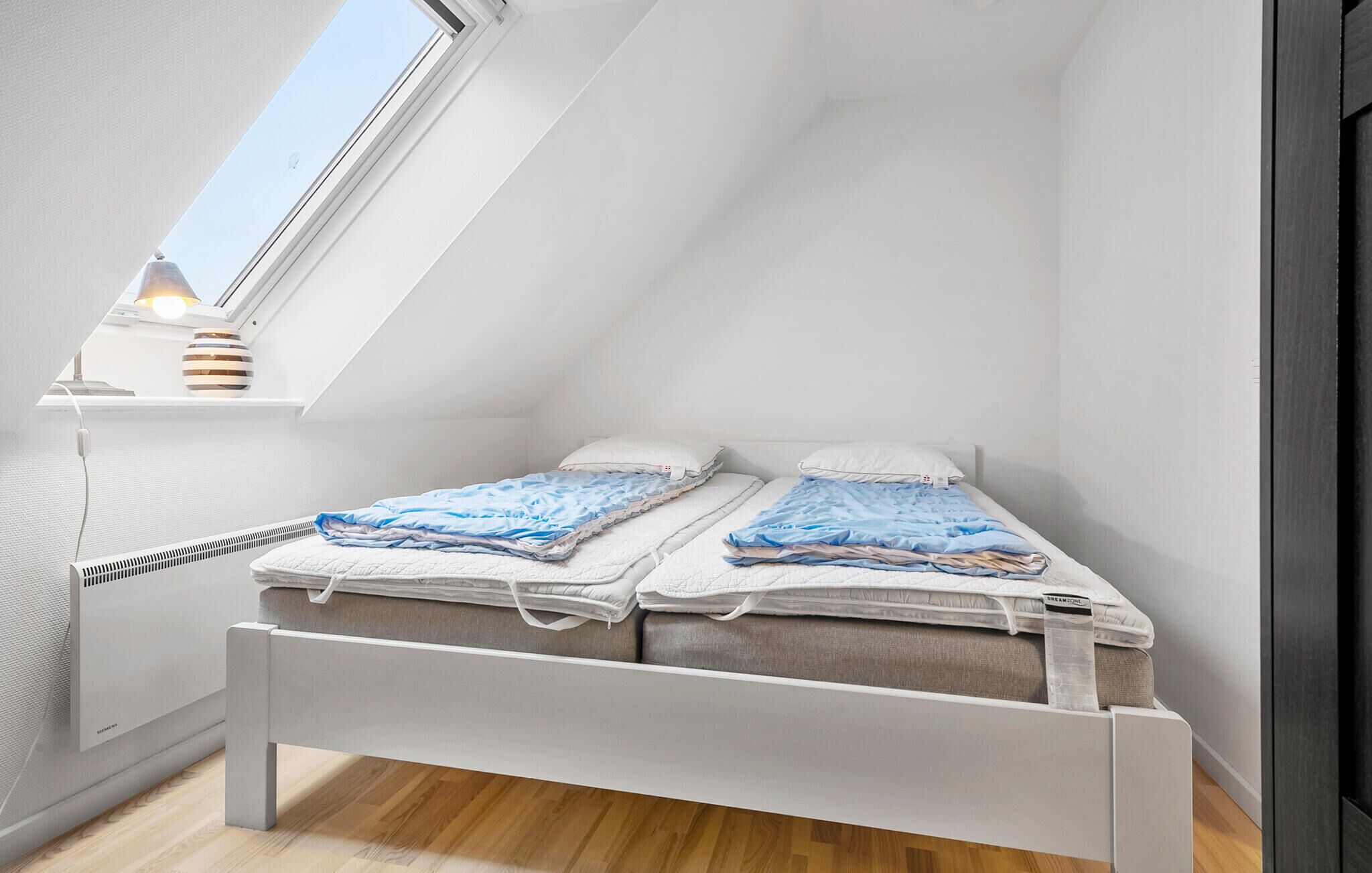 Ein kleines Schlafzimmer im Loft-Stil mit zwei Betten, einem Oberlicht und einer Heizung.