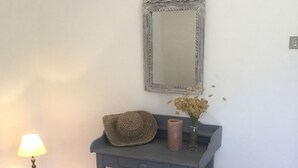 Ein Holzboden, ein dunkelblauer Konsolentisch, eine Lampe, ein Spiegel und eine gewebte Tasche.