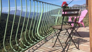 Ein Balkon mit Metallgeländer, einem Holztisch und zwei Stühlen.