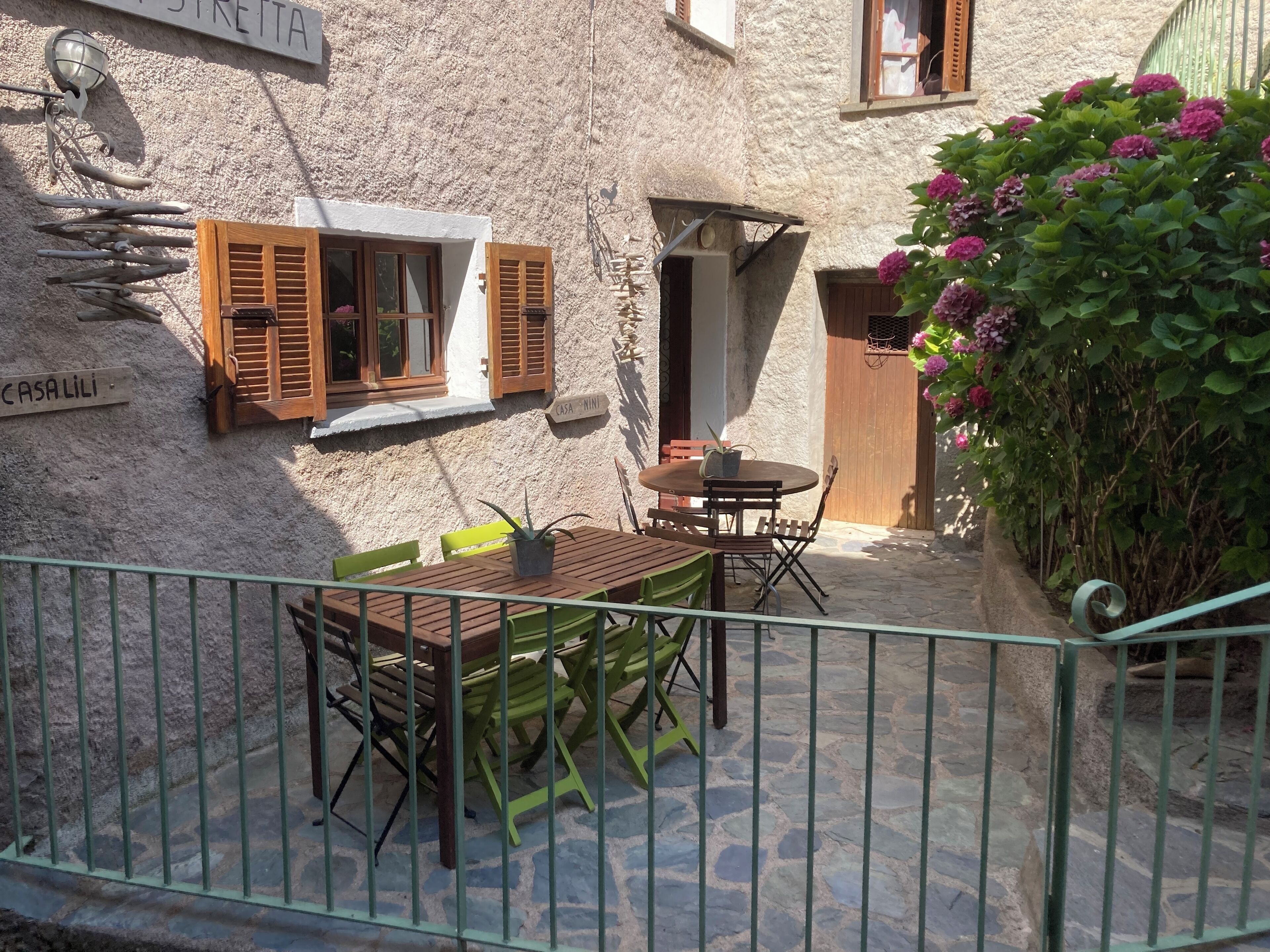Ein Innenhof mit Holztisch und -stühlen, einem Blumentopf und einer Steinmauer.