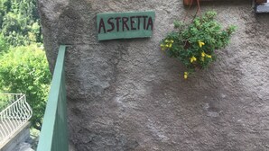 Eine rustikale Steinmauer mit einem Holzfenster und einem Schild mit der Aufschrift 'ASTRETTA'.