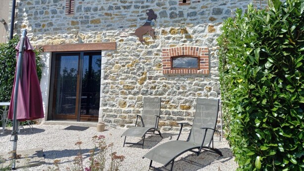 A stone building with a brick oven, outdoor seating, and a large window.