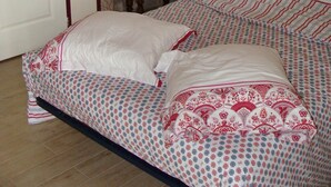 A bedroom with a bed, pillows, a bedside table with a lamp, and a door.