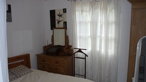 A bedroom with a bed, wooden dresser, mirror, and a window with sheer curtains. - Guest house 1 air-conditioned bedroom with private bathroom and bedroom wc (Porto-Vecchio)