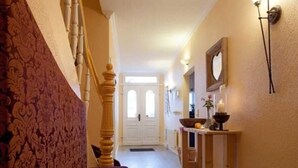 A hallway with a wooden staircase, a bench, a table with a bowl and fruit, and a mirror on the wall. - Comfort room - Aparthotel Waldfrieden (Sellin)