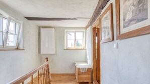A narrow hallway with wooden flooring, a wooden railing, and a small bench with a white cloth. There are two windows and a door on the right side. - Vacation in a monument; Relax in the Geo-Naturpark Frau-Holle-Land, 4 DTV * (Berkatal-Hitzerode)