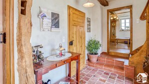 A rustic interior with a wooden door, a wooden desk with a lantern, a potted plant, and a tiled floor. - Vacation in a monument; Relax in the Geo-Naturpark Frau-Holle-Land, 4 DTV * (Berkatal-Hitzerode)