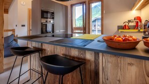 A modern kitchen with a central island, bar stools, and a view of a mountain. - K-Terra 4 : Recent and modern chalet with hot tub (MONTRIOND)