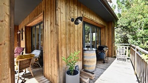 A wooden deck with outdoor seating, a barbecue grill, and a large barrel. - Villa at the extreme point of Cap Ferret (Cap Ferret)