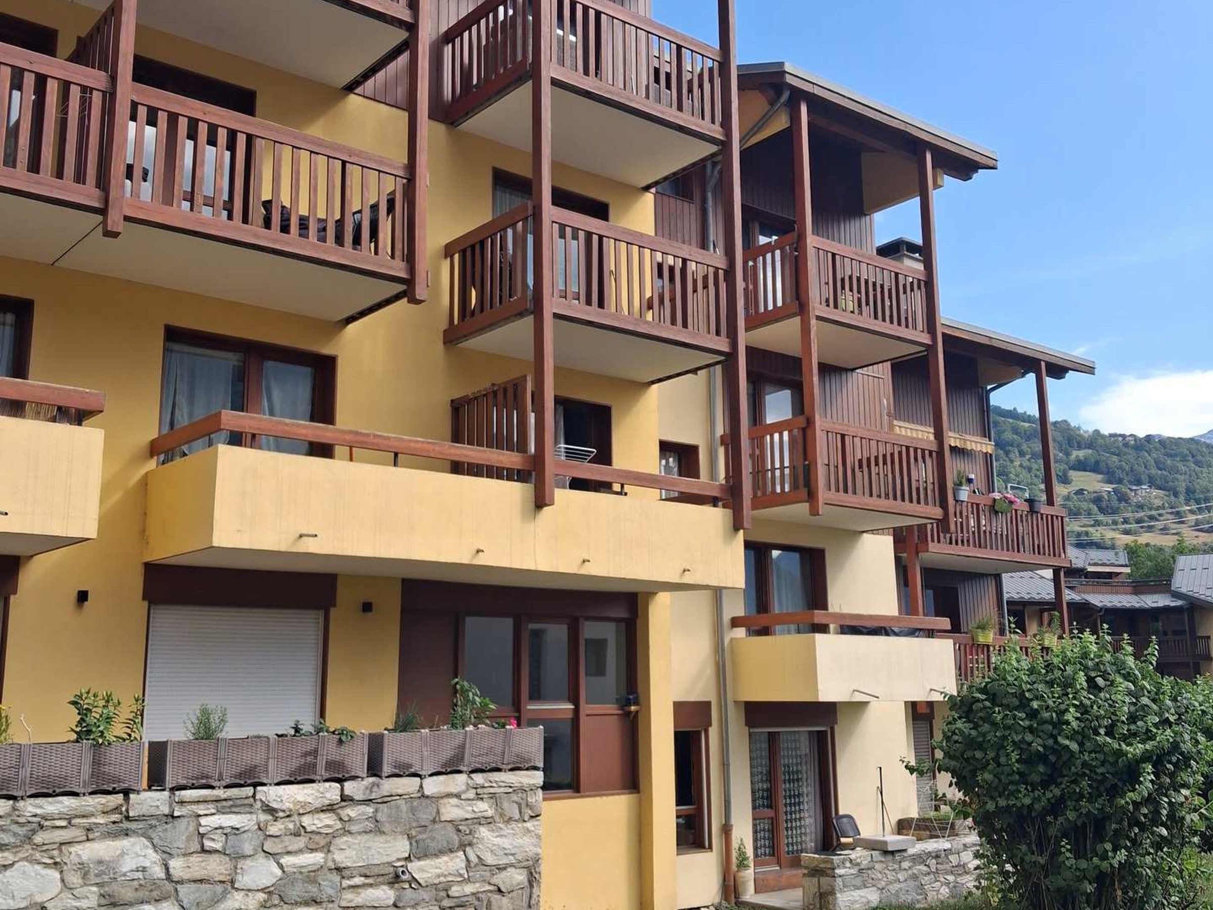 Un immeuble à plusieurs étages doté de balcons, avec une fondation en pierres et offrant une vue dégagée sur le paysage environnant.