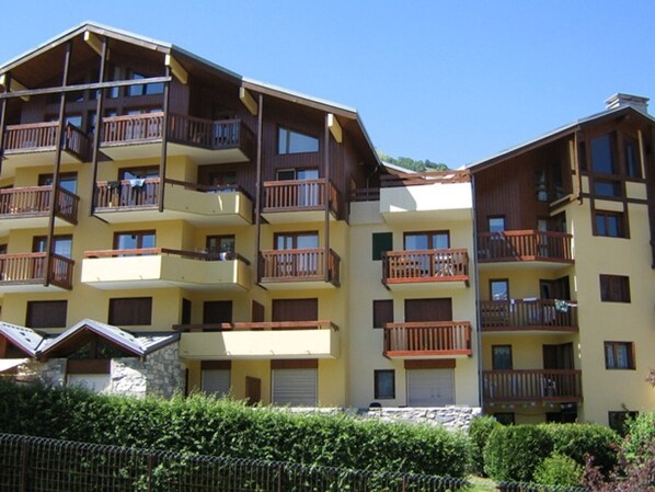 A multi-story hotel with balconies, a stone facade, and a clear sky.