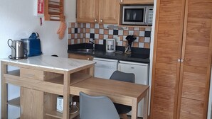 A compact kitchen with wooden cabinets, a microwave, a coffee maker, and a sink.