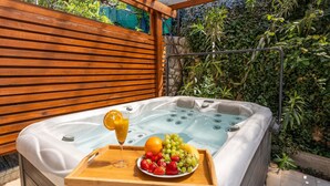 Ein Whirlpool mit einer Holzbank, einer Obstschale und einem Glas Orangensaft.
