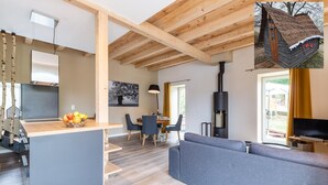 Una sala de estar moderna con un sofá gris, un comedor con mesa y sillas, una cocina con encimera de madera y un amplio ventanal.