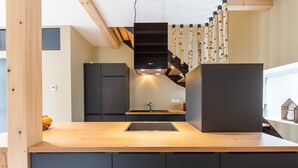 Una cocina moderna con encimera de madera, armarios negros y una campana extractora negra.