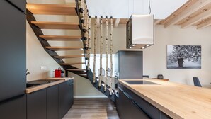 Una cocina moderna con una escalera de madera, una isla integrada y un ventanal grande.