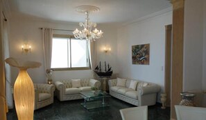 A living room with two sofas, a glass coffee table, a chandelier, and a large floor lamp. - Promenade des Anglais, stunning views, dream apartment (Nice)