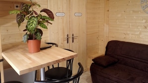 Un intérieur en bois avec une table, une plante en pot, un canapé et un téléviseur fixé au mur.