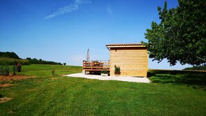 Une cabane en bois avec un toit en tuiles, un banc et un petit jardin.