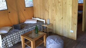 A cozy room with two beds, a fan, a small table, and a window. - Casa Maya Samara ECOLODGE (Sámara)