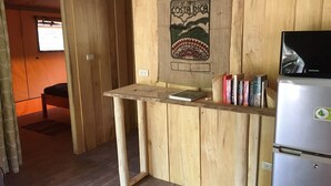 A wooden-framed desk with a laptop and books, a Samsung refrigerator, and a window with a view of the outdoors. - Casa Maya Samara ECOLODGE (Sámara)