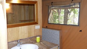 A bathroom with a wooden vanity, a sink, a mirror, and a window with a view of trees. - Casa Maya Samara ECOLODGE (Sámara)