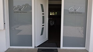 Ein Hotelzugang mit Milchglasüren, auf denen das Logo "Au Grès des Vosges" zu sehen ist, und Blick ins Innere.