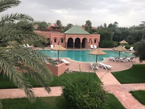 Un complex turístic amb una piscina gran, palmeres i gandules.