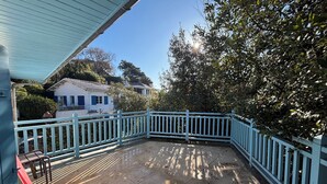 A covered patio area with a blue railing, a tiled floor, and a view of a white house in the background. - House Ville d'Hiver, Arcachon center - 2 bedrooms - Parquet (Arcachon)