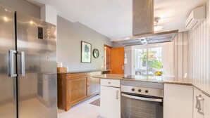 A modern kitchen with stainless steel appliances, a wooden cabinet, and a view to the outside. - Holiday Home "Villa Mar - Can Bujosa" on the Beach (Palma de Mallorca)