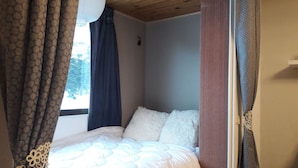 Ein Schlafzimmer mit einem Bett, Vorhängen und einem Fenster.