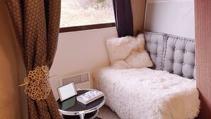 Ein gemütliches Zimmer mit einem Bett, einem kleinen Tisch mit einem Laptop und einem Fenster mit Vorhängen.