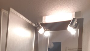 Ein Badezimmer mit einem weißen Waschbecken, einem Spiegel und einem Regal darüber.