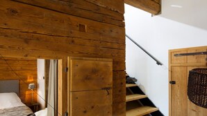 A wooden staircase leading to a loft bedroom with a bed and a small table. - 5-Bedroom Chalet, Sauna, Norwegian Bath, Wifi, Sleeps 12 in La Clusaz (La Clusaz)