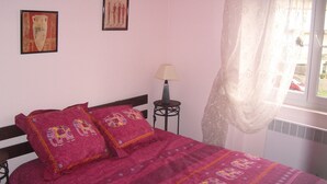 Camera da letto con un letto, due cuscini, un comodino, una lampada e due quadri appesi al muro.