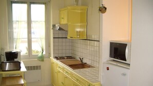 Una cucina compatta con mobili gialli, un lavello, un forno a microonde e un tostapane.