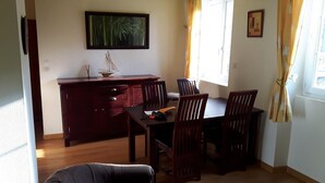 Un'area pranzo con un tavolo in legno, sedie, un piccolo mobile e un quadro appeso al muro.