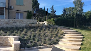 Un muro de piedra con escalones que conducen a una casa con persianas verdes.