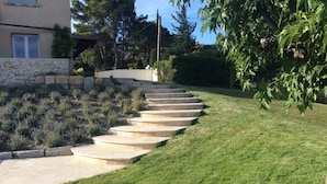 Una escalera de piedra que sube por una pendiente cubierta de césped, con un edificio al fondo.