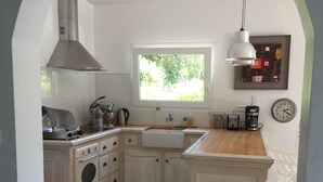 A kitchen with a large window, white cabinetry, a built-in oven, and a hanging light fixture.