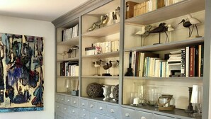 A spacious room with a large grey cabinet with multiple drawers and shelves, filled with books, decorative items, and a large abstract painting on the wall.