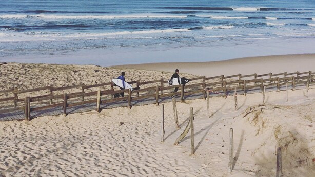A sandy beach with a wooden fence and ocean waves.