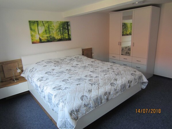 A bedroom with a bed, a nightstand, a wardrobe, and a painting on the wall. - House Innerste, Germany (Wildemann)