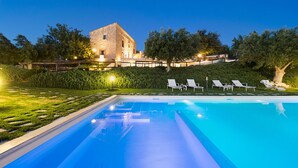 A swimming pool with lounge chairs and a stone building in the background. - Villa with pool, wellness area and private tennis court (Scicli)