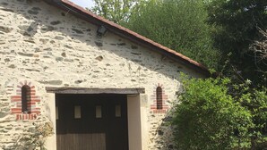 Ein rustikales Steinhaus mit einer großen Holztür und zwei kleinen Fenstern.